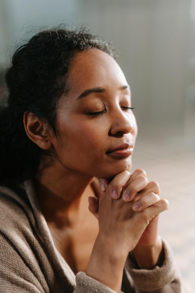 Close-up of a woman praying, conveying a sense of peace and faith.