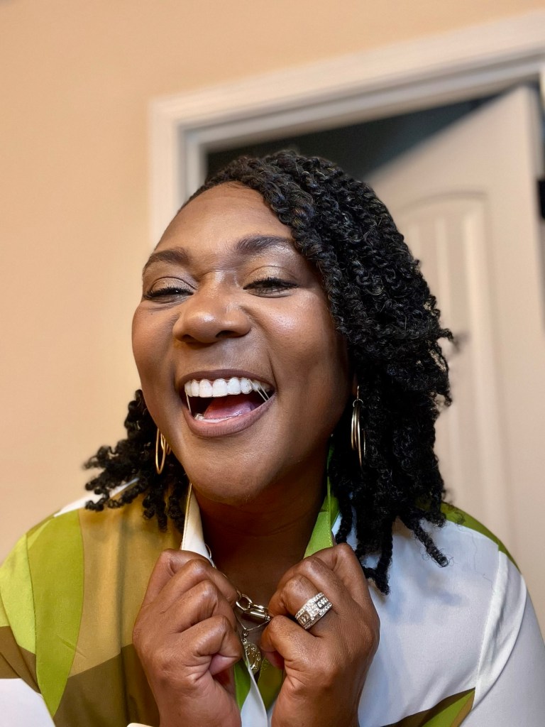 Dawn Charleston-Green smiling wearing green and tan dress with hair in twists