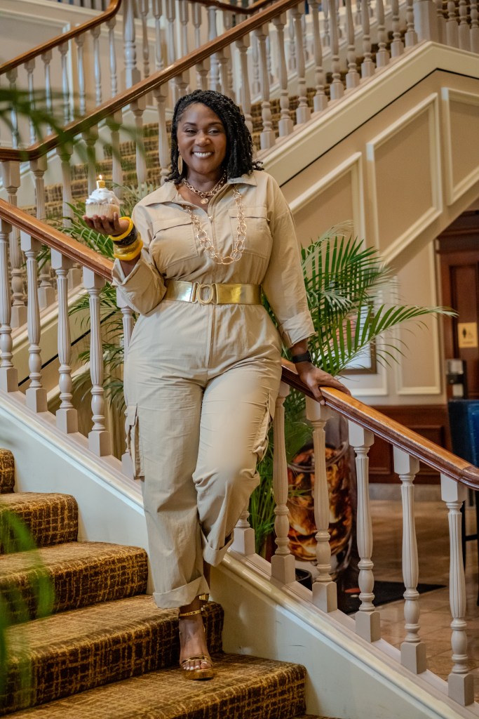 Dawn Charleston-Green standing on a grand staircase holding a cupcake with a #5 candle on top of it. 