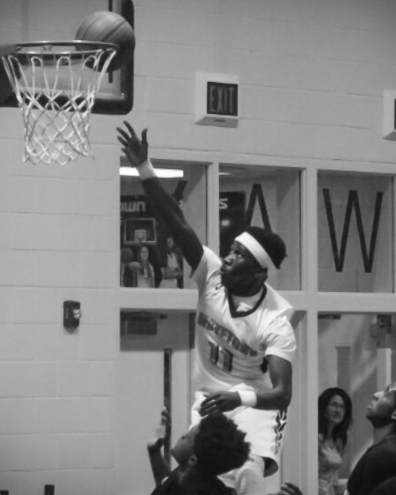 Rudy Valentine intently playing high school basketball shooting a jump shot close to the rim. 